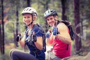 Young happy biker couple sitting on a rock looking at the camera