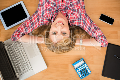 Smiling woman lying on floor surrounded by office items