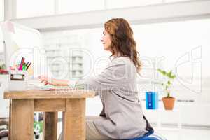 Casual businesswoman sitting on exercise ball while working