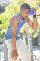 An handsome athlete leaning a bottle against his head