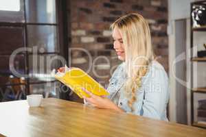 Smiling blonde reading yellow book