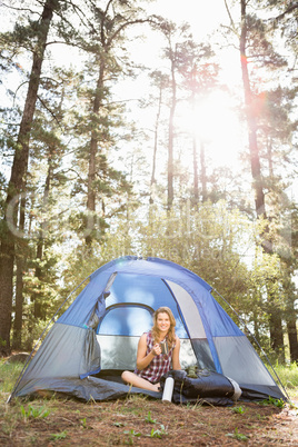 Pretty blonde camper smiling and sitting in tent