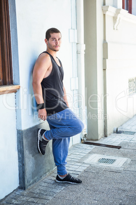 Portrait of a handsome athlete leaning against a wall