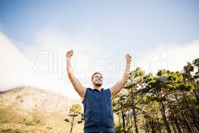 Young happy jogger standing on rock and cheering