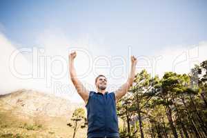 Young happy jogger standing on rock and cheering