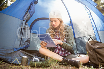 Pretty blonde camper using tablet and sitting in tent