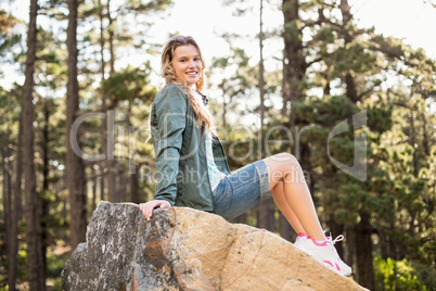 Young happy jogger sitting on rock and looking at camera