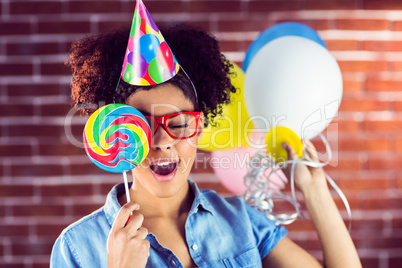 Young woman holding balloons and lollipop