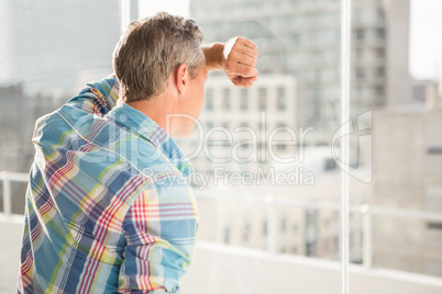 Troubled casual businessman leaning against window