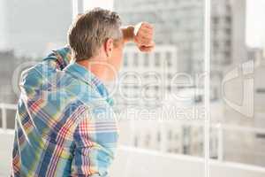 Troubled casual businessman leaning against window