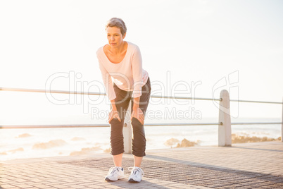 Breathing sporty woman resting at promenade