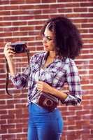 Attractive hipster holding camera and looking at it