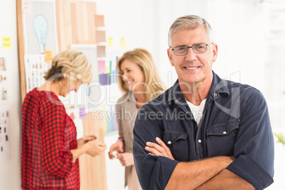 Businessman with arms crossed with his team behind