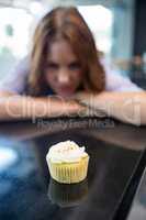 Pretty brunette looking at cupcake