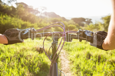 Woman mountain biking and holding handlebars