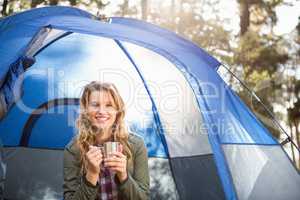 Pretty blonde camper smiling and sitting in tent