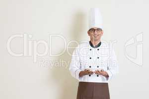 Handsome Indian male chef in uniform holding a plate