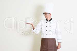 Handsome Indian male chef in uniform holding an empty plate