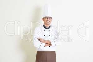 Handsome Indian male chef in uniform with kitchen tools