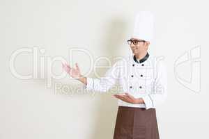 Handsome Indian male chef in uniform showing something