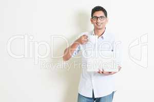 Casual business Indian male using computer and drinking tea