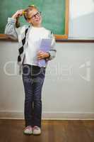 Cute pupil thinking and holding books in a classroom