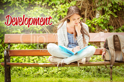 Development against smiling student sitting on bench reading boo