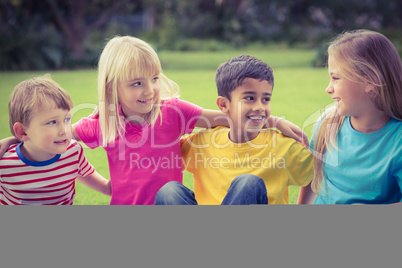 Smiling classmates talking and sitting in grass