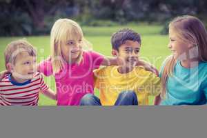 Smiling classmates talking and sitting in grass