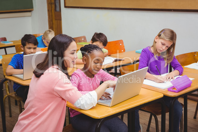 Happy teacher using laptop with student