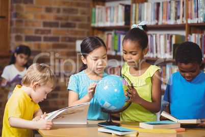 Pupils studying globe in the library