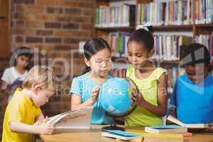 Pupils studying globe in the library