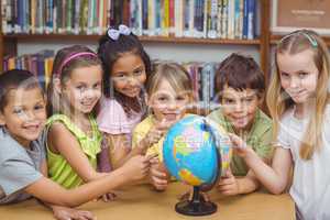 Pupils in library pointing to globe