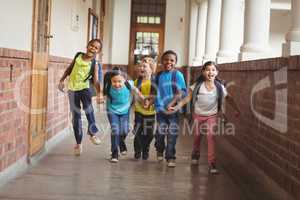 Happy pupils holding hands and running at corridor