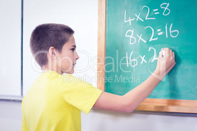 Cute pupil calculating on chalkboard in a classroom