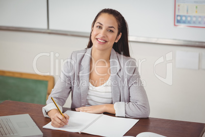 Pretty teacher correcting at her desk in a classroom
