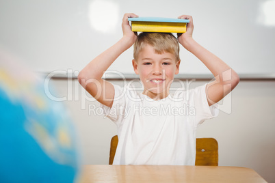 Pupil holding book over his head