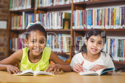 Smiling pupils reading books in the library