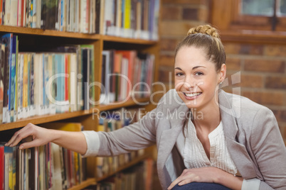Blonde teacher searching book in the library