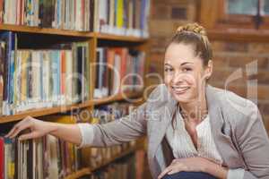 Blonde teacher searching book in the library