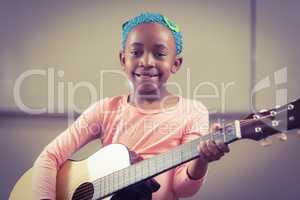 Smiling pupil playing guitar in a classroom