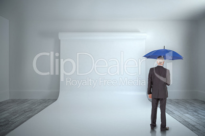 Composite image of businessman holding umbrella