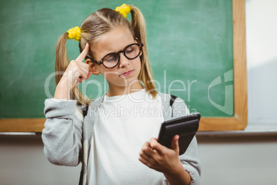 Cute pupil calculating with calculator in a classroom