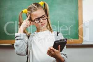 Cute pupil calculating with calculator in a classroom