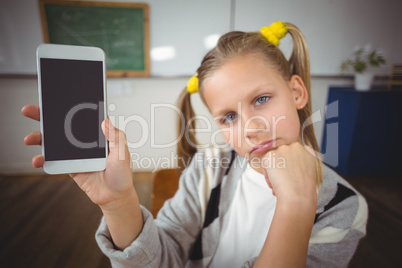 Cute pupil showing smartphone to camera