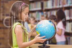 Pupil in library looking at globe