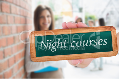 Night courses against pretty student smiling and holding notepad