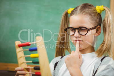 Cute pupil calculating with abacus in a classroom