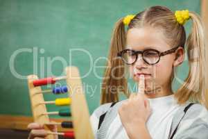 Cute pupil calculating with abacus in a classroom