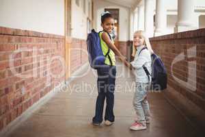 Smiling pupils holding hands at corridor